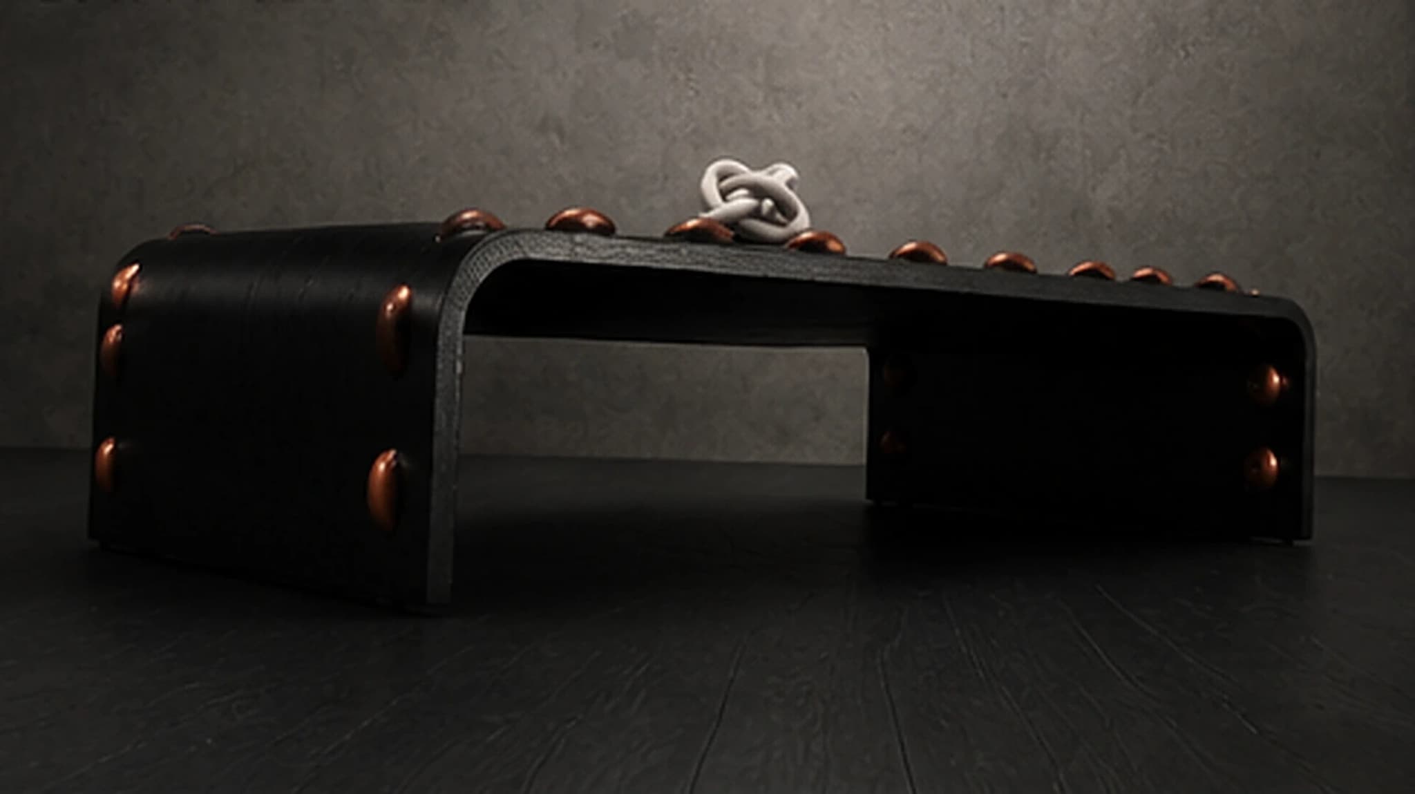 The Leather Stud Coffee Table, a low dramatic angle showing the black leather waterfall form and thread studs
